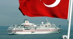 A white ship sails in the waters and a Turkish flag flutters