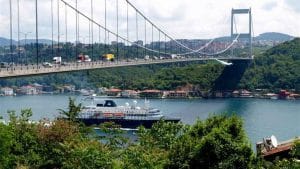 A ship crossing the water passes under a suspension bridge on both banks of the Bosphorus Strait