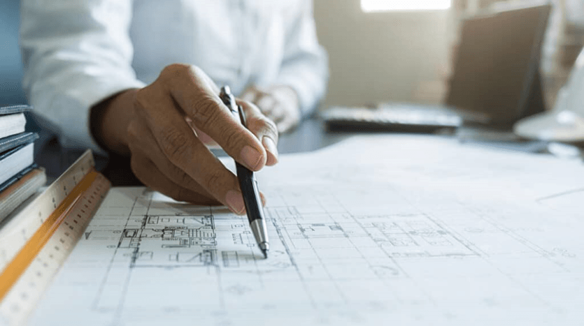 مخطط هندسي على ورقة بيضاء وشخص يمسك قلم أسود ويشير للخريطة