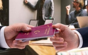 A person hands another person two Turkish passports