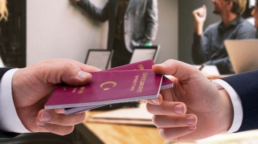 A person hands another person two Turkish passports