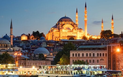 A mosque surrounded by residential buildings and illuminated by lights at night